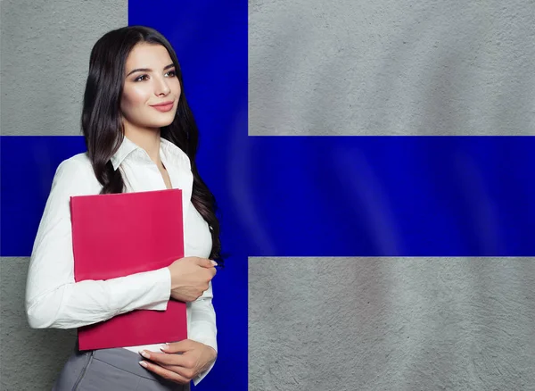 フィンランドの旗の背景に赤い本を持つ幸せなスマート女性 教育又は事業の概念 — ストック写真