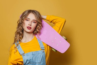 Parlak sarı arka planda kaykaylı kız