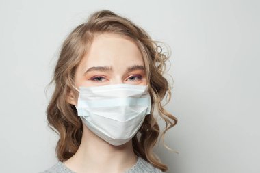 Tıbbi maske takan genç bir kadın. Grip salgını ve virüs koruma kavramı