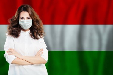 Macaristan bayrağına karşı yüz maskeli hemşire. Grip salgını ve virüs koruma kavramı