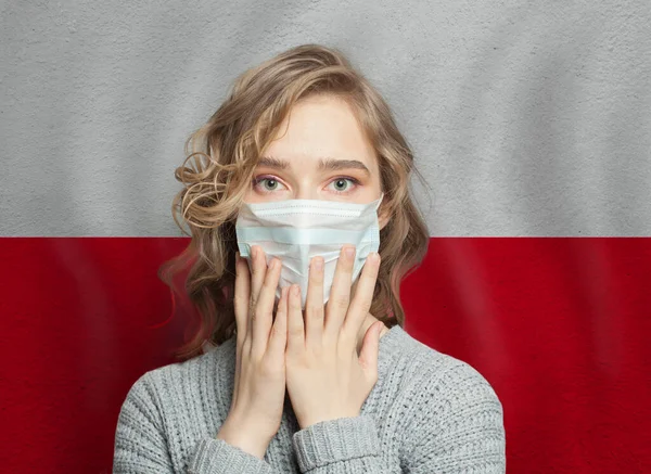 Polonya bayrağı geçmişi olan tıbbi maskeli, korkmuş bir kadın. Polonya 'da grip salgını ve aile içi şiddet
