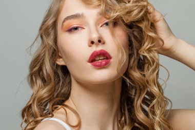 Beyaz arka planda uzun sarı kıvırcık saçlı, güzel bir yüzü olan mükemmel bir kadın.