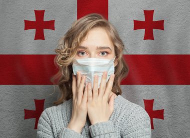 Gürcistan bayrağı geçmişi olan tıbbi maskeli bir kadın. Gürcistan 'da grip salgını ve aile içi şiddet