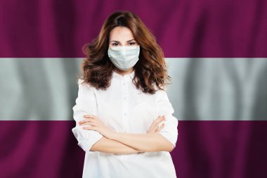 Letonya bayrağına karşı yüz maskeli hemşire. Grip salgını ve virüs koruma kavramı