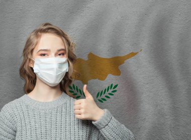 Kıbrıs bayrağı geçmişine parmak kaldıran maskeli mutlu kadın. Grip salgını ve virüs koruma kavramı