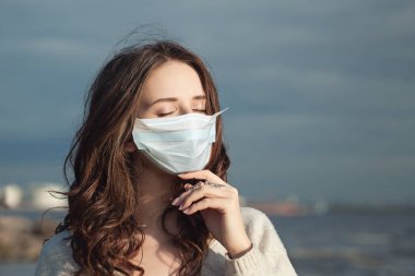 Koruyucu maskeli güzel kadın açık havada yaz güneşinin tadını çıkarıyor.