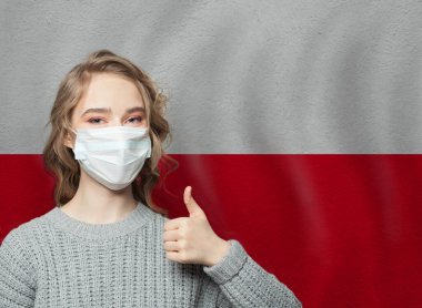 Yüz maskeli mutlu kadın Polonya bayrağının arkasında başparmak kaldırıyor. Grip salgını ve virüs koruma kavramı