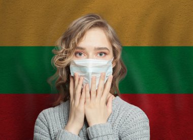 Litvanya bayrağı geçmişi olan, tıbbi maskeli, korkmuş bir kadın. Litvanya konseptinde grip salgını ve aile içi şiddet