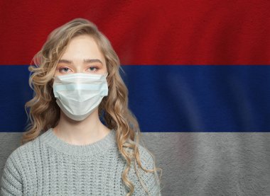 Sırbistan bayrağı taşıyan yüz maskesi takan genç bir kadın. Grip salgını ve virüs koruma kavramı