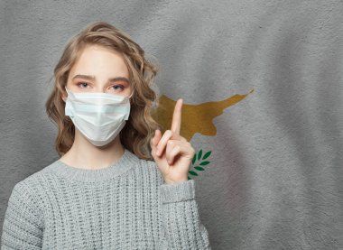 Tıbbi maskeli kadın Kıbrıs Bayrağı geçmişine bakıyor. Grip salgını ve virüs koruma kavramı