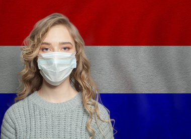 Hollanda bayrağı taşıyan yüz maskesi takan genç bir kadın. Grip salgını ve virüs koruma kavramı