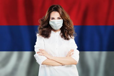 Sırbistan bayrağına karşı maskeli iyimser bir doktor. Grip salgını ve virüs koruma kavramı