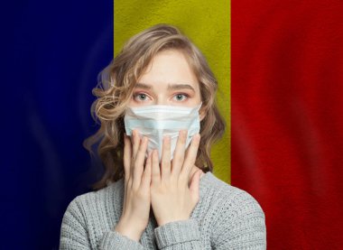 Romanya bayraklı arka planda tıbbi maskeli korkmuş kadın. Romanya 'da grip salgını ve aile içi şiddet kavramı