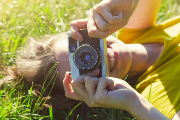 Sorrindo menina deitada na grama com câmera de filme — Fotografia de Stock