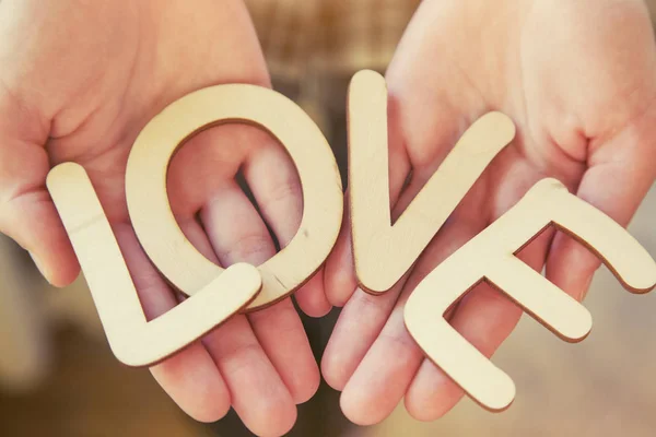 Χέρια που κρατούν ξύλινα γράμματα με τη λέξη αγάπη. Έννοια της αγάπης — Φωτογραφία Αρχείου