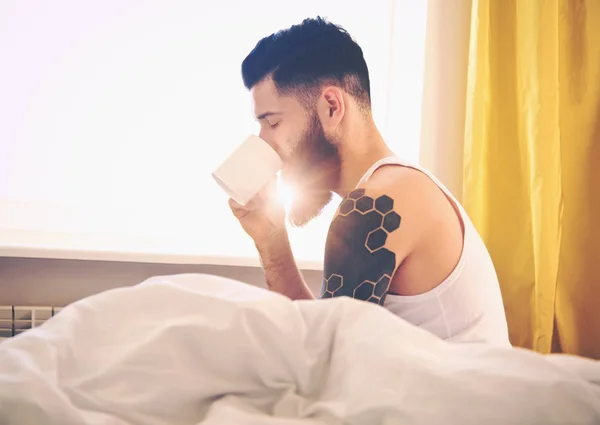 Uomo barbuto a letto bere caffè — Foto Stock