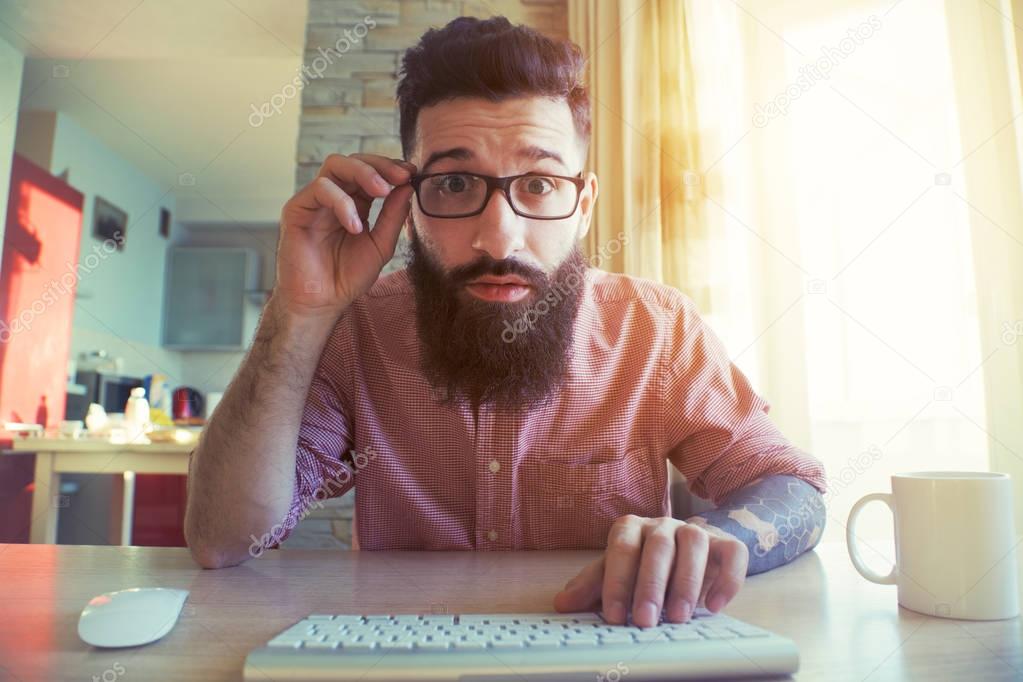 Funny bearded man looking at computer