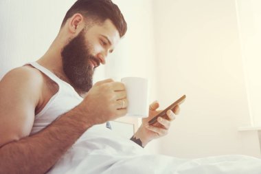 Sakallı adam Kupası ile yatakta yatan 