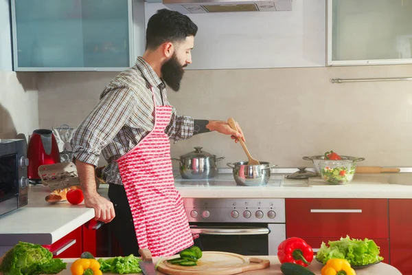 Удивительный бородатый мужчина готовит на кухне, делая здоровым — стоковое фото