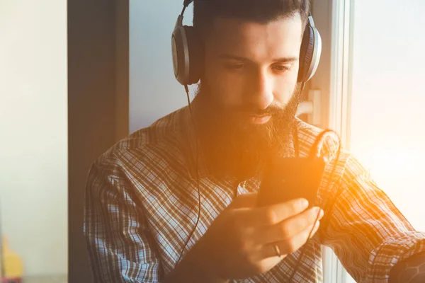 Бородатий чоловік в навушниках слухає музику — стокове фото