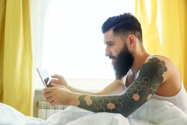 Dijital tablet ile sabah yatakta adam 