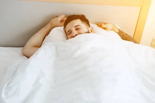 Mann im Bett hebt die Hände — Stockfoto