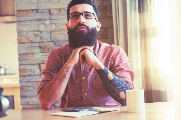 Bearded man in glasses sitting at table — Stock Photo, Image