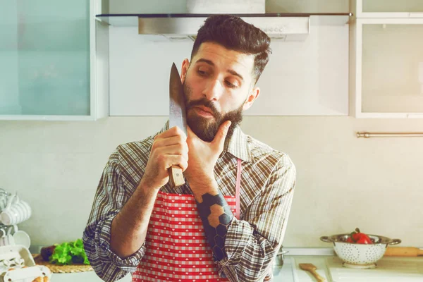 Pohledný muž legraci v kuchyni, s nožem — Stock fotografie