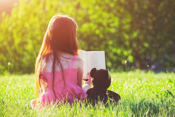 Meisje lezen boek met teddy bear speelgoed — Stockfoto