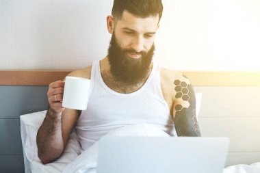 dizüstü bilgisayar kullanarak ve kahve içme adam