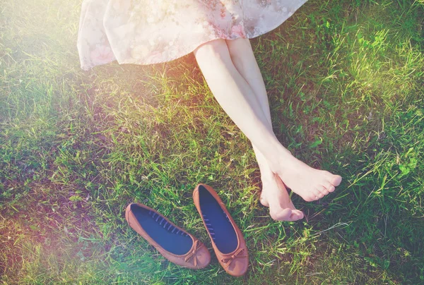 Pernas femininas deitado na grama — Fotografia de Stock