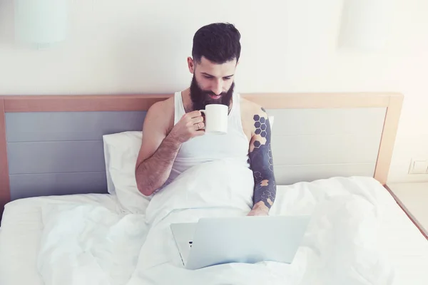 Man using laptop and drinking coffee — Stock Photo, Image