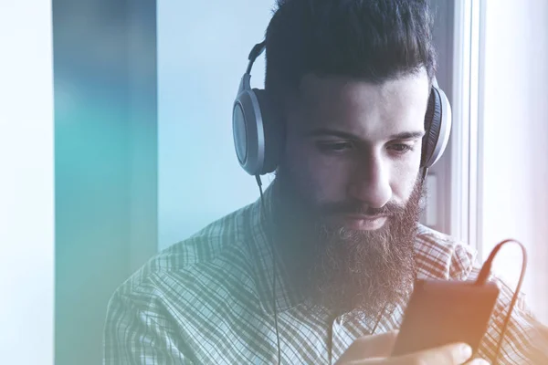 Бородатый мужчина в наушниках слушает музыку — стоковое фото