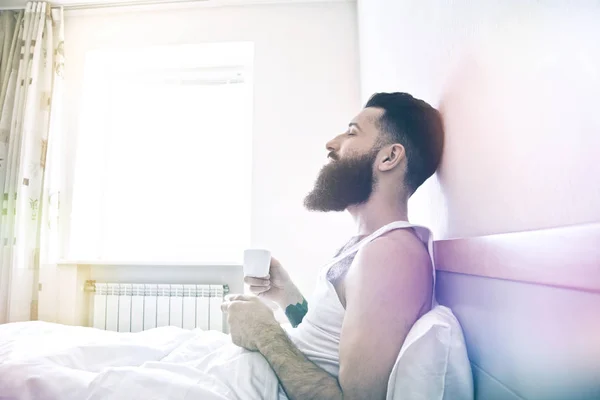 Mann sitzt im Bett und trinkt Kaffee — Stockfoto