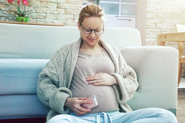 Mujer embarazada poniendo teléfono en el vientre — Foto de Stock