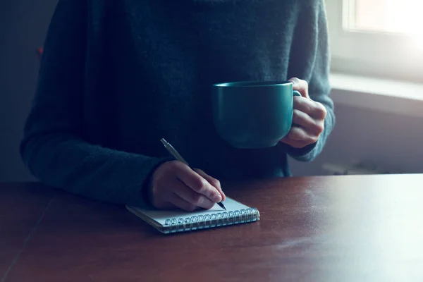 Kvinnliga händer med penna och cup — Stockfoto