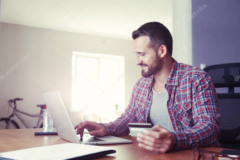 Man holding credit card and using laptop
