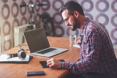 Dijital tablet, dizüstü bilgisayar ve kalem masada konsantre adamla