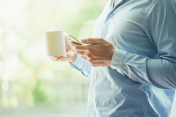 Affärsman Hand Hålla Morgonkaffe Och Läsande Telefonerna — Stockfoto