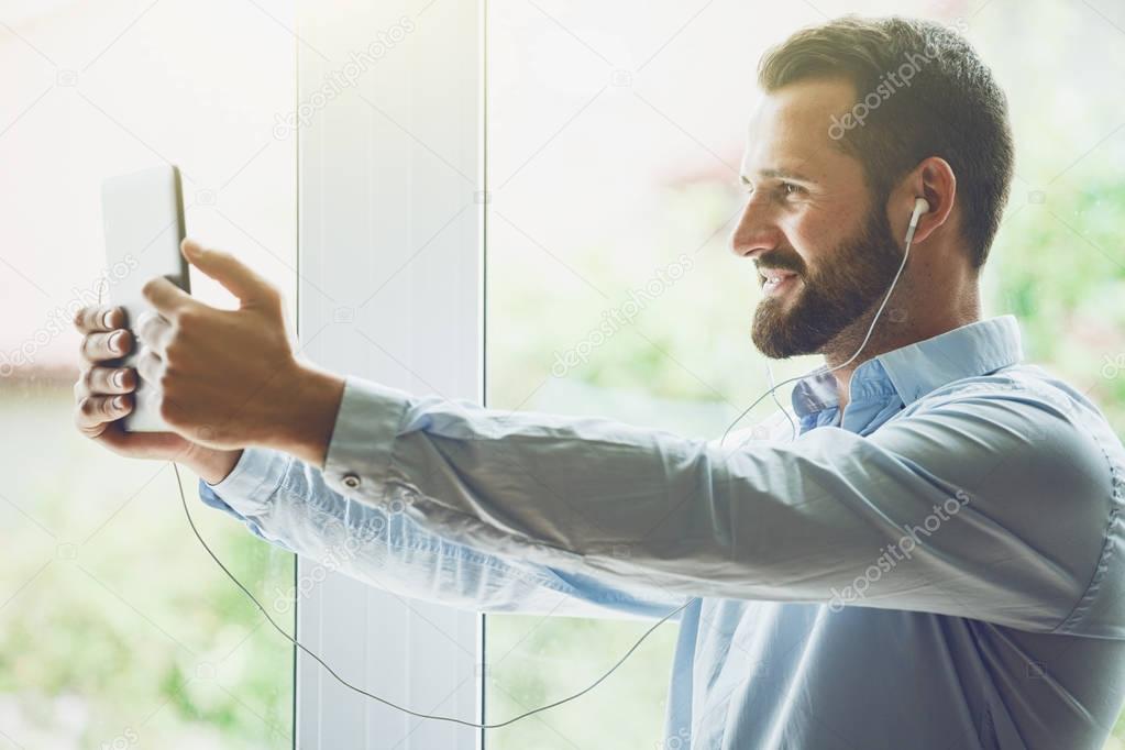smiling businessman with digital tablet and earphones calling with video conference