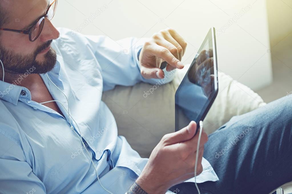smiling businessman with digital tablet and earphones calling with video conference