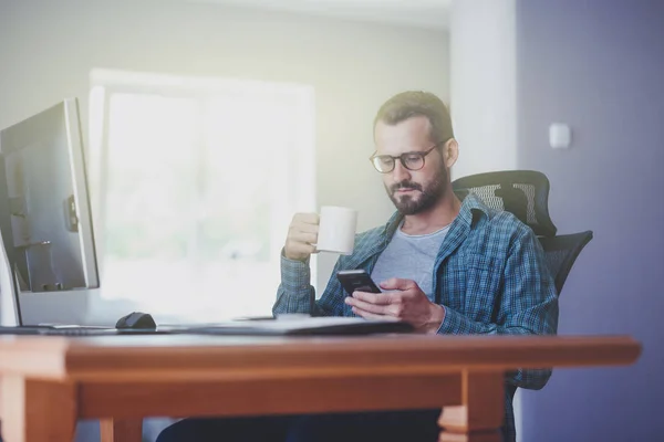 Man met slimme telefoon en kopje thee — Stockfoto