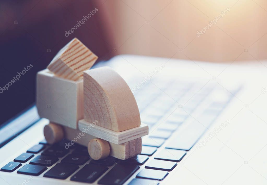 Wooden toy truck on laptop keyboard. Internet shopping, on-line purchase, e-commerce and packages delivery concept.