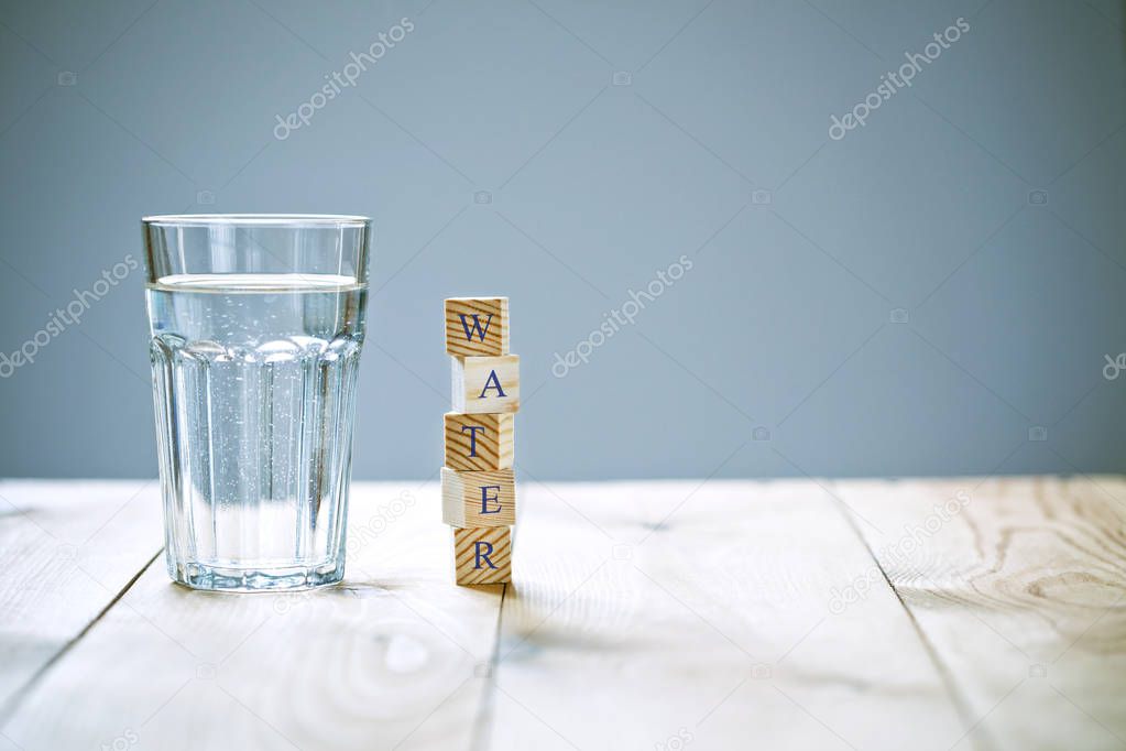 Glass of pure water with word written in wooden blocks