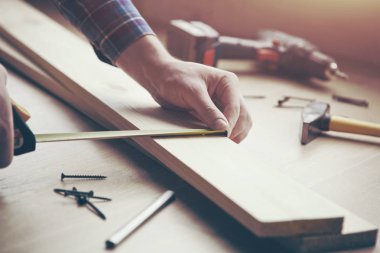 Erkek eli ahşap mezurayla çalışıyor.