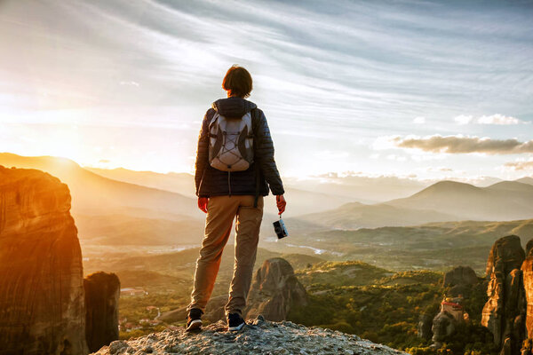 woman with camera enjoying sunset on top of mountain 