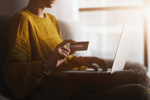 Frau hält Kreditkarte und tippt mit Laptop Informationen ein. Online-Einkaufen und Bezahlen im Internet während der Coronavirus-Quarantäne — Stockbild Frau Hält Kreditkarte Und Tippt Mit Laptop Informationen Ein Online — Stockfoto