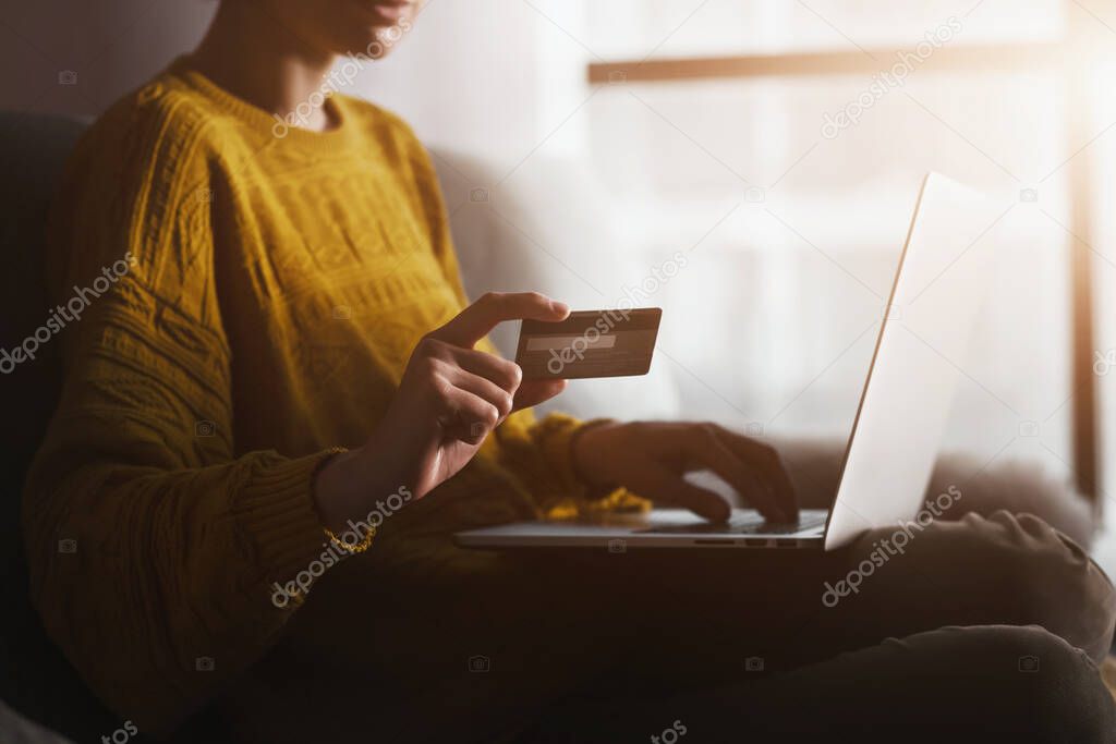 Woman holding credit banking card and typing information with laptop. Online shopping and paying in internet during coronavirus quarantine