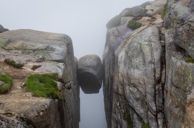 Kjerag stone, hanging on the cliff between two high rocks. clipart
