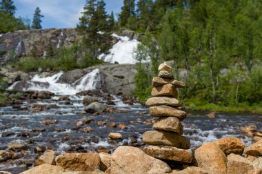 Şelale arka plan üzerinde geleneksel Norveç taş piramit.